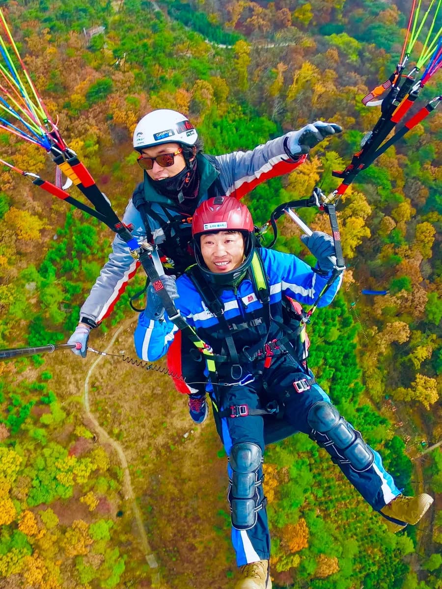 Vol biplace en parapente au-dessus d'une forêt d'automne