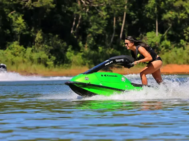 Une pilote debout sur un jet-ski vert, en virage