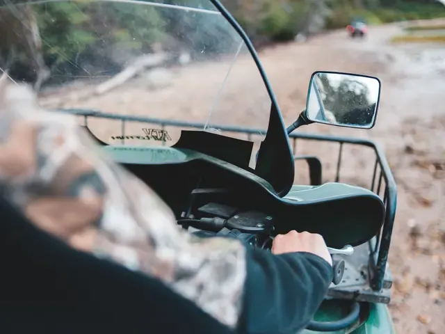 Les mains d'un pilote sur le guidon d'un quad, dans la boue